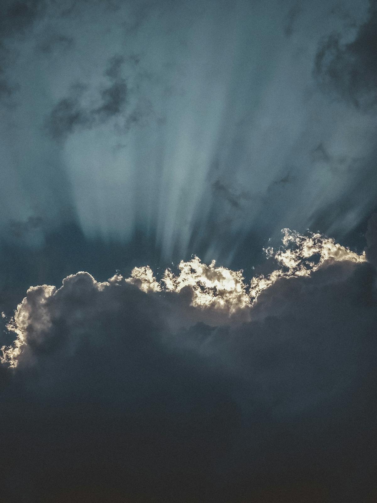 Dramatic sun rays breaking through dark storm clouds