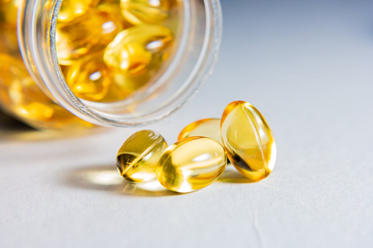 Close-up of zinc supplement softgel capsules spilling from a glass jar
