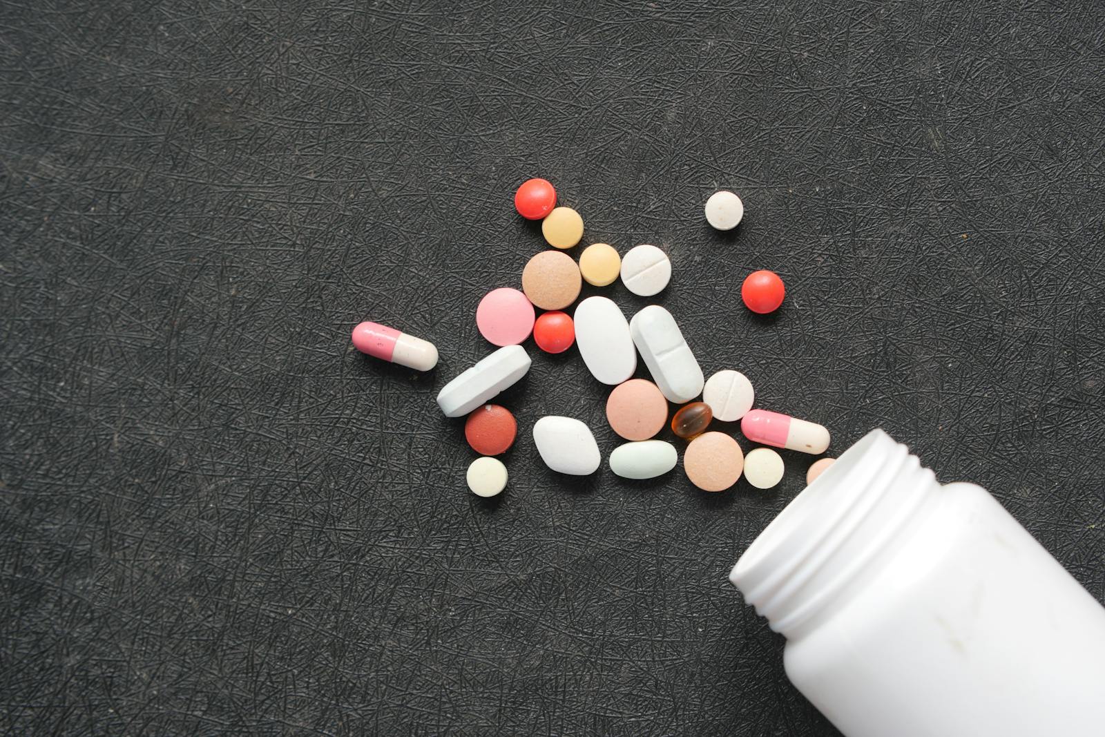 Assorted choline supplement capsules spilling onto a dark surface